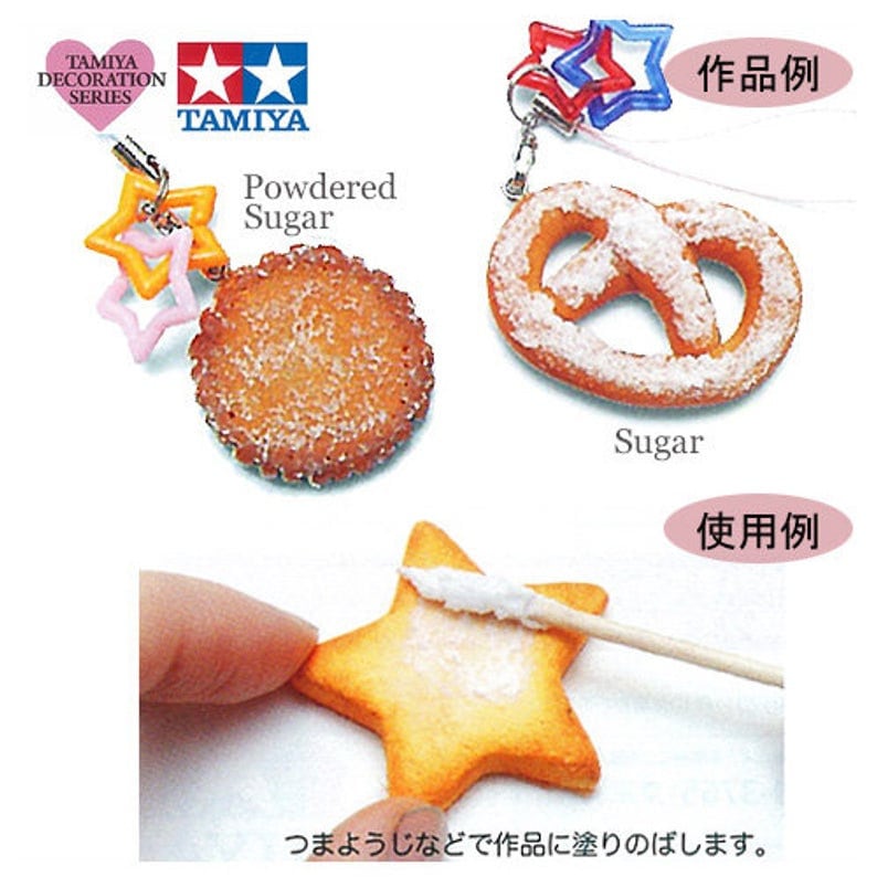 May include: A close-up of a small, white, powdered sugar container with a star-shaped cookie and a pretzel. The container is labeled "Powdered Sugar" and is part of the Tamiya Decoration Series. The image also shows a hand using a toothpick to apply powdered sugar to a star-shaped cookie.