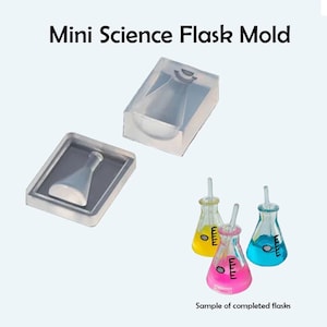 Könnte beinhalten: Zwei transparente Silikonformen zum Herstellen von Miniatur-Wissenschaftskolben. Die Formen sind rechteckig und haben ein erhabenes Design eines Kolbens mit rundem Boden und langem Hals. Das Bild zeigt auch drei fertige Kolben in Rosa, Gelb und Blau.