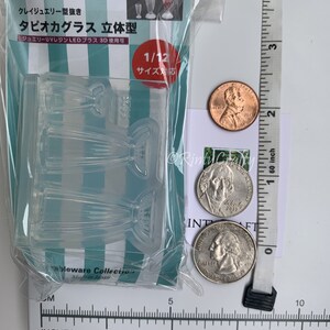 May include: Clear plastic mold for making miniature tapioca bubble tea glasses. The mold is 1/12 scale and is designed for use with UV resin or LED resin. The mold is packaged in a clear plastic bag with a green and white striped background. The package also includes a picture of three miniature tapioca bubble tea glasses.