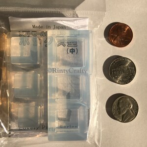 May include: A clear silicone mold with four square cavities. The mold is labeled "Lovely Part Series" and has Japanese text that reads "Made in Japan" and "Soft Seal". The mold is packaged in a clear plastic bag with three US coins for scale.