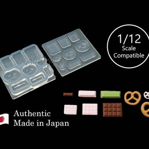 Peut inclure: Un moule en silicone transparent avec 10 formes différentes pour réaliser des miniatures d'aliments. Le moule comprend des formes pour des bretzels, des barres chocolatées et d'autres friandises. Le moule est compatible avec les maisons de poupées à l'échelle 1/12. Le texte "Authentic Made in Japan" est imprimé sur l'image.