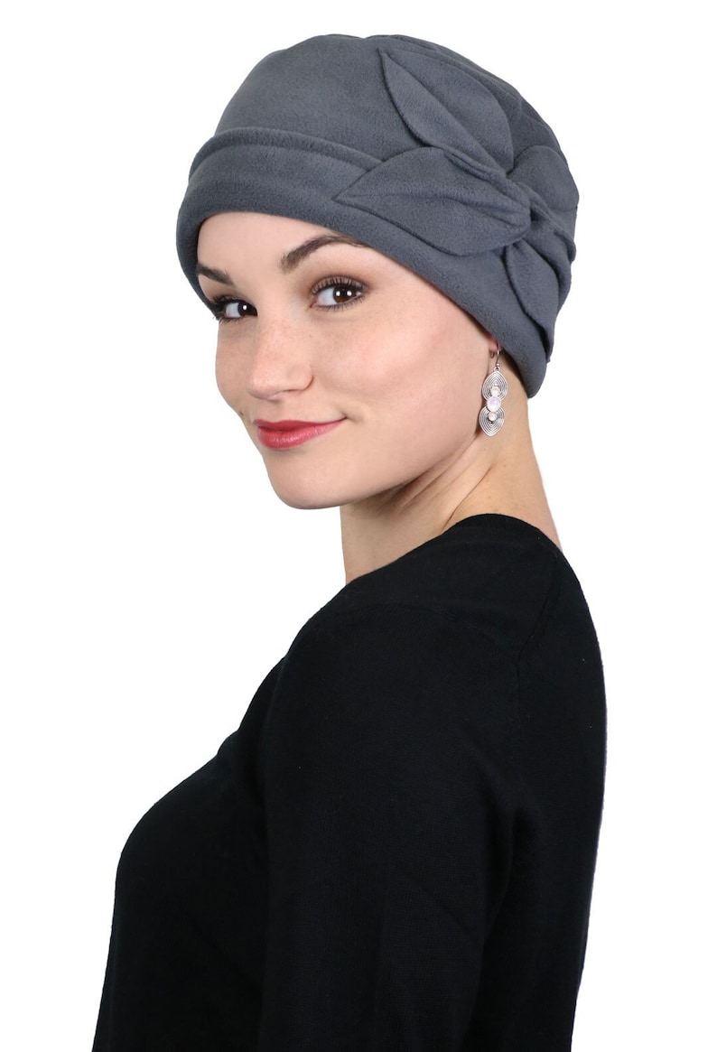 Pode incluir: Um gorro de l&atilde; cinza com um grande la&ccedil;o dobrado de um lado. O gorro &eacute; macio e confort&aacute;vel, e &eacute; perfeito para manter a cabe&ccedil;a quente no inverno.