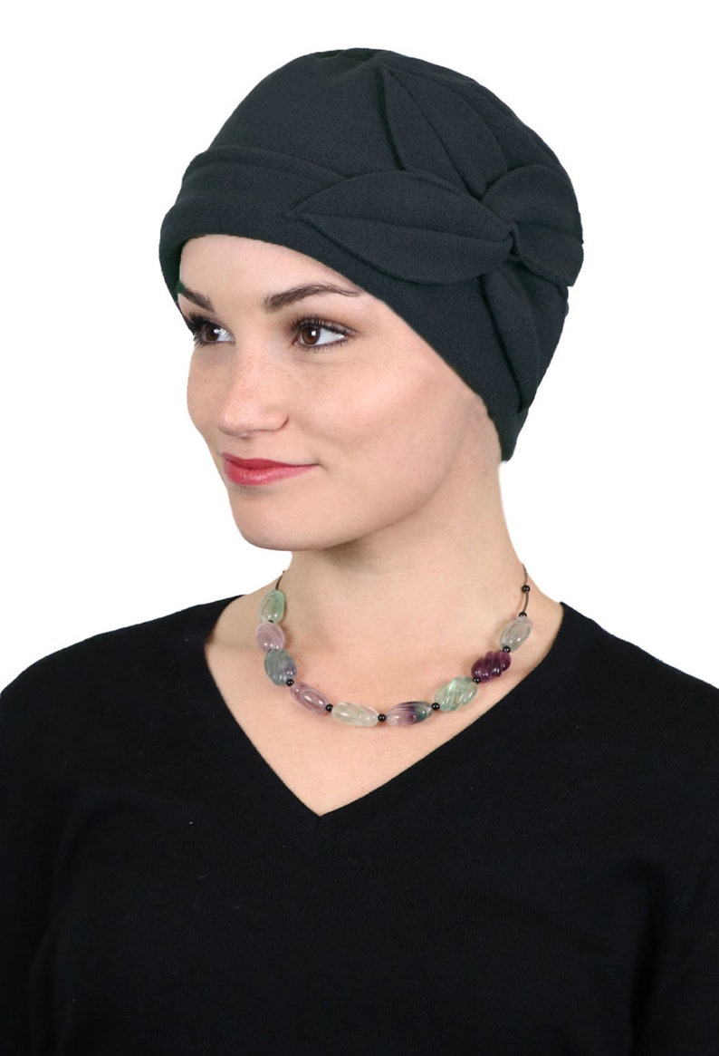 Pode incluir: Um gorro de l&atilde; verde escuro com um design de folhas. O gorro &eacute; usado por uma pessoa com um colar de contas verdes, roxas e pretas.