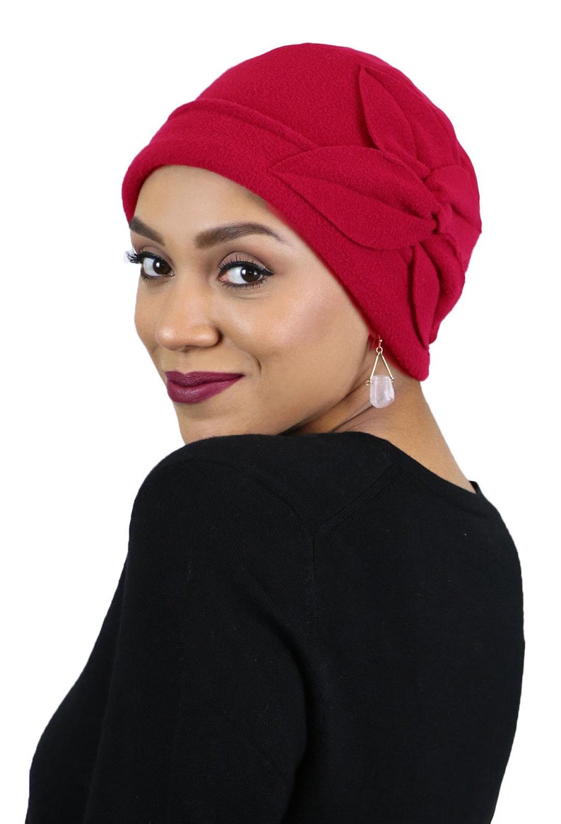 Pode incluir: Um gorro de l&atilde; vermelho com um design em forma de flor no topo. O gorro &eacute; macio e confort&aacute;vel e &eacute; perfeito para manter a cabe&ccedil;a quente no inverno.