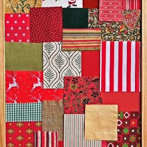 May include: A wooden frame containing a collage of various fabric swatches in red, green, gold, and white. The patterns include Santa Claus figures, white reindeer on red, stripes, plaids, floral prints, stars, and geometric shapes in a grid.