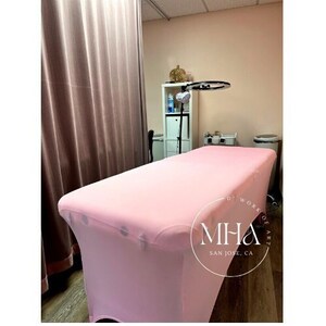 Peut inclure: Un drap housse rose pour table de massage. Le drap est lisse et sans plis. Le drap est sur une table dans une pièce avec un éclairage annulaire et d'autres meubles. Le texte sur le drap est "Work of Art" et "MHA San Jose, CA".