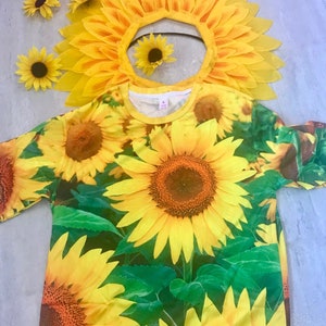 May include: A yellow t-shirt with a sunflower print. The shirt has a crew neck and short sleeves. A yellow sunflower headband is also included.