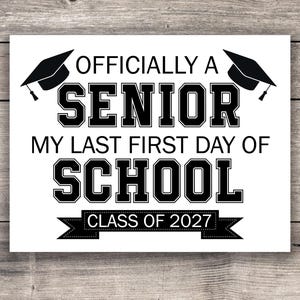 Puede incluir: Un letrero blanco con texto negro y gráficos de gorras de graduación. El texto dice: "OFICIALMENTE UN SENIOR, MI ÚLTIMO PRIMER DÍA DE ESCUELA, CLASE DE 2027". El letrero está sobre un fondo de madera.