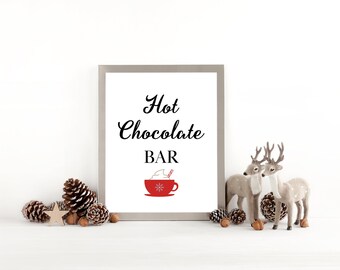 Puede incluir: Una impresión enmarcada con las palabras "Hot Chocolate BAR" en escritura negra. Un gráfico de taza roja con crema batida y un bastón de caramelo está debajo del texto. Piñas decorativas, una estrella, bellotas y figuras de ciervos rodean el marco.
