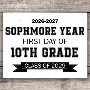 Puede incluir: Un letrero blanco con texto negro sobre un fondo de madera. El letrero dice "2026-2027 SOPHMORE YEAR FIRST DAY OF 10TH GRADE CLASS OF 2029". El texto está en negrita y en un tipo de letra grueso.