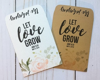 May include: Two brown paper seed packets with the text "Let love grow" and the names "Jade & DJ" and the date "May 4, 2019". The packets have a floral design with pink and green watercolor flowers.