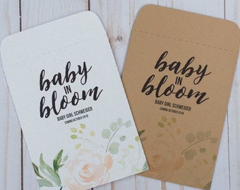 May include: Two announcement cards with the text "baby in bloom". One card is white with floral accents and the other is brown. The text "BABY GIRL SCHWEIGER COMING OCTOBER 2018" is also present.
