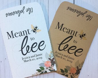 May include: Two white and brown paper favor bags with a bee design and the text "Meant to bee" with the names Jessica and Jamie and the date March 10, 2019.