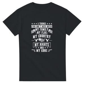 Puede incluir: Camiseta negra con texto blanco. El texto dice: "5 COSAS CON LAS QUE NO TE METAS: MI FAMILIA, MI BANDERA, MI PAÍS, MIS DERECHOS Y MIS ARMAS." El diseño incluye estrellas, banderas y pistolas.
