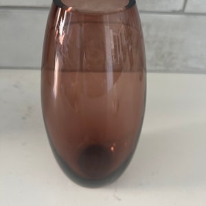 May include: A dark brown glass vase with a rounded, oval shape.