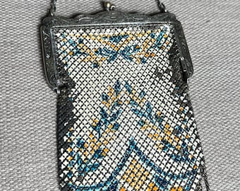 May include: A vintage silver mesh purse with a chain strap and a floral pattern. The purse has a fringe detail and a silver clasp.