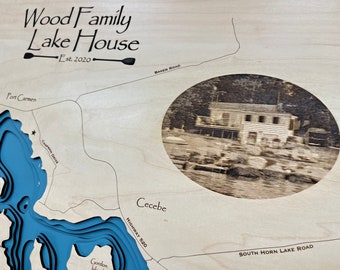 May include: A wooden plaque with a laser-engraved map of a lake, featuring the text "Wood Family Lake House Est. 2020" at the top. The map includes the names of various locations around the lake, such as "Port Carmen", "Chapran Drive", "Gordon Island", "Cecebe", "Highway 520", and "South Horn Lake Road". A circular photo of a lake house is also included in the map.