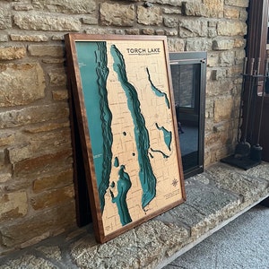 Wooden custom lake map with real wood frame leaning against a fireplace.