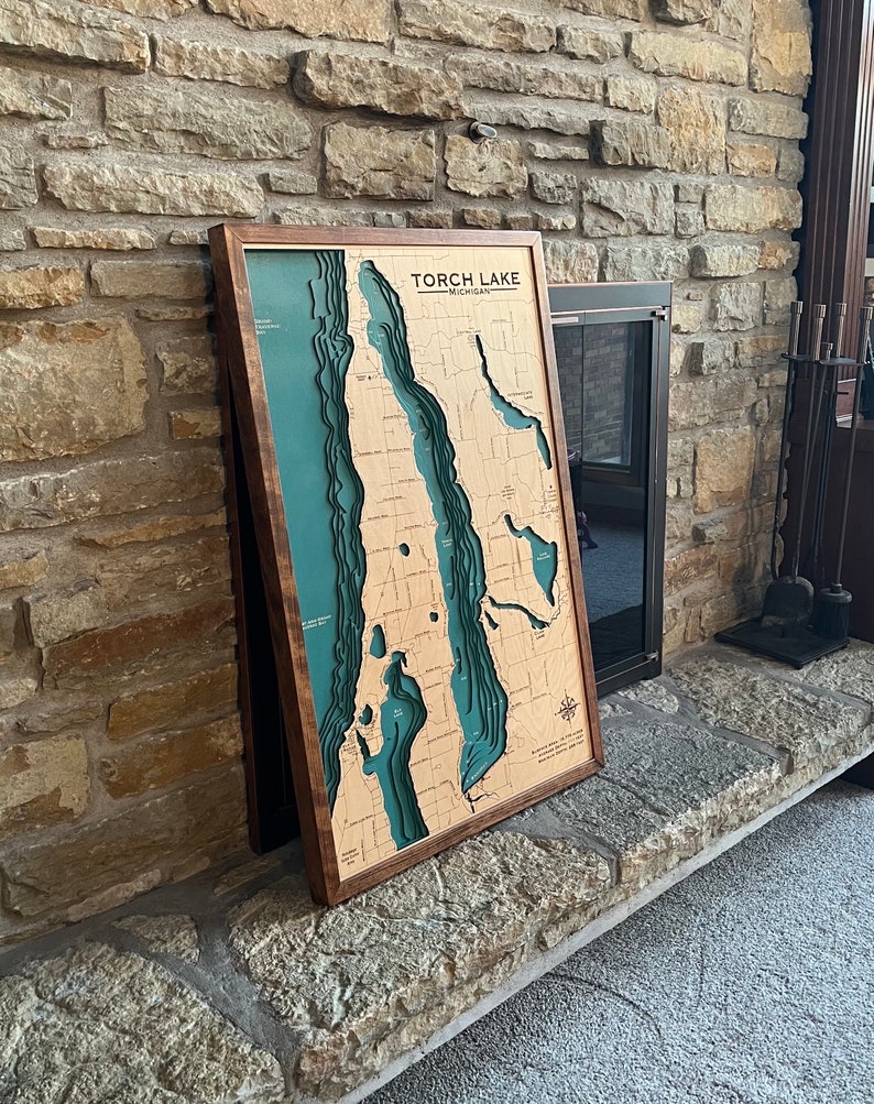 Wooden custom lake map with real wood frame leaning against a fireplace.