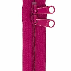 May include: A pink zipper with two pull tabs. The zipper is closed and the pull tabs are in the up position.