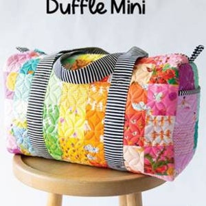 May include: A colorful patchwork duffle bag with a striped handle and accents. The bag is made of various patterned fabrics in a rainbow of colors, including pink, yellow, green, and orange. The text "Patchwork Duffle Mini" is displayed above the bag.