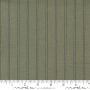 May include: A close-up of a green and white striped fabric with a subtle linen texture. The fabric is measured in inches with a ruler.