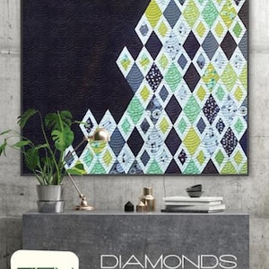 May include: A quilt pattern featuring a diamond design in shades of green, blue, and yellow. The quilt is framed and hanging on a wall. The text "Zen Chic" and "Diamonds and Grey" is visible below the quilt.