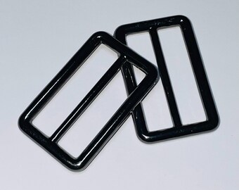 May include: Two black metal slider buckles. The buckles are rectangular with a smooth, shiny finish.