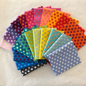 Puede incluir: Una colección de cuadrados de tela doblados en un arcoíris de colores, cada uno adornado con un patrón de lunares. Las telas están dispuestas en forma de abanico, mostrando una variedad de tonos, incluyendo rosa, naranja, verde y azul.