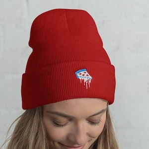 Puede incluir: Un gorro rojo con un gráfico de una rebanada de pizza blanca y azul. El gorro está hecho de un material suave y cálido, perfecto para mantener la cabeza caliente en invierno.