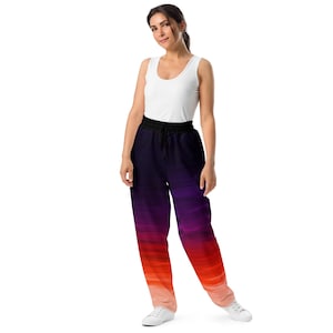 Puede incluir: Pantalón de chándal de color degradado morado y naranja con cintura elástica negra. El pantalón de chándal tiene un corte holgado y está hecho de un tejido suave y cómodo.