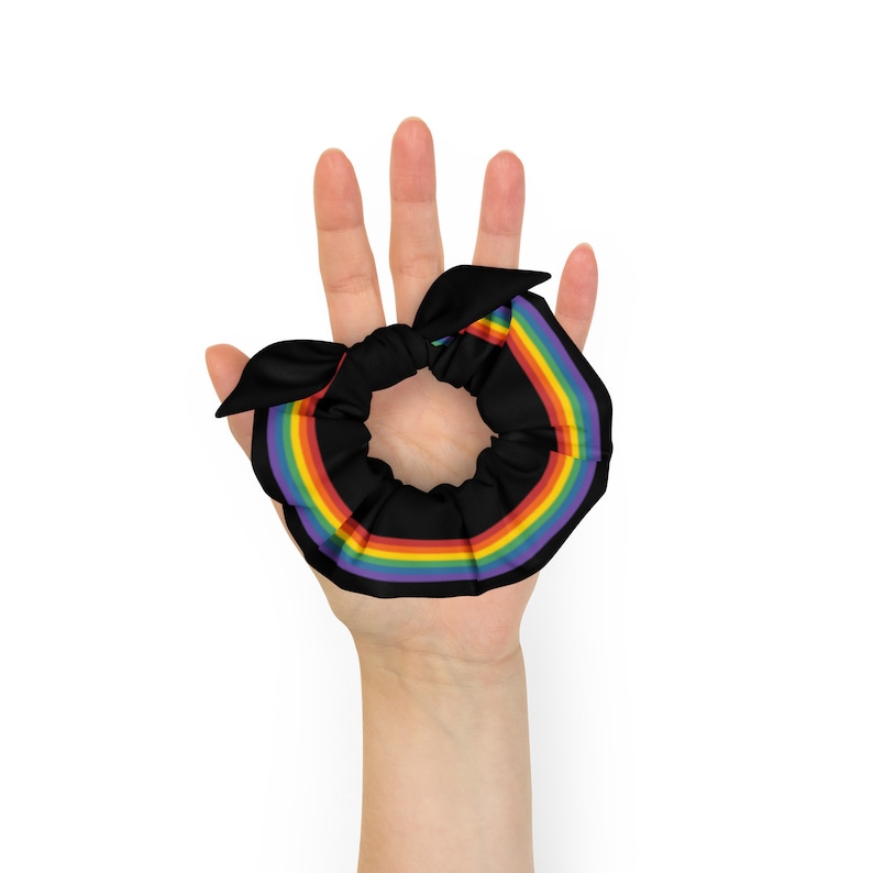 May include: A black hair scrunchie with a rainbow stripe design. The scrunchie is made of soft fabric and is perfect for holding hair in place.
