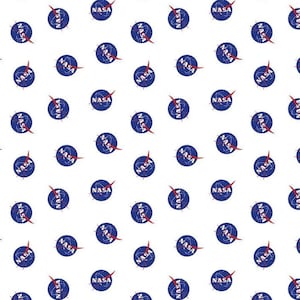 May include: White fabric with a repeating pattern of the NASA logo. Each logo is a blue circle with the NASA text in white and a red vector graphic. The fabric has a ruler along the bottom edge.