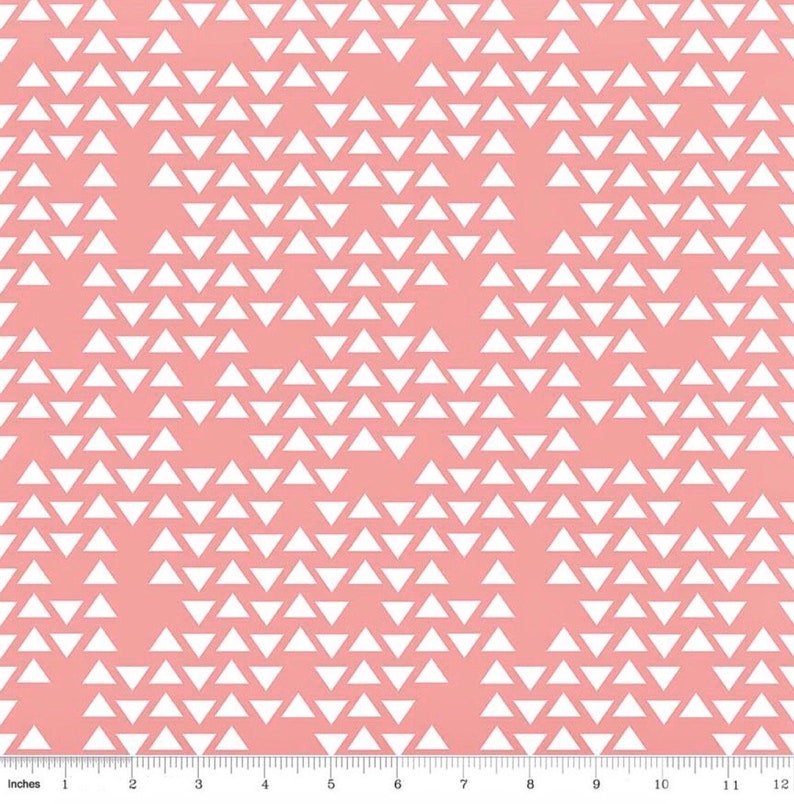 Op de afbeelding: Een roze stof met een wit geometrisch patroon van herhalende driehoeken. De driehoeken zijn in een verspringend patroon gerangschikt, waardoor een subtiel chevron-effect ontstaat.