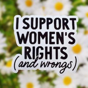 May include: A white sticker with black text that reads "I SUPPORT WOMEN'S RIGHTS (and wrongs)". The sticker is set against a blurred background of white daisies with yellow centers and green foliage.