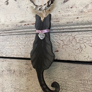 May include: Black wooden cat silhouette ornament with a pink ribbon and a silver charm that says "Love My Cat".