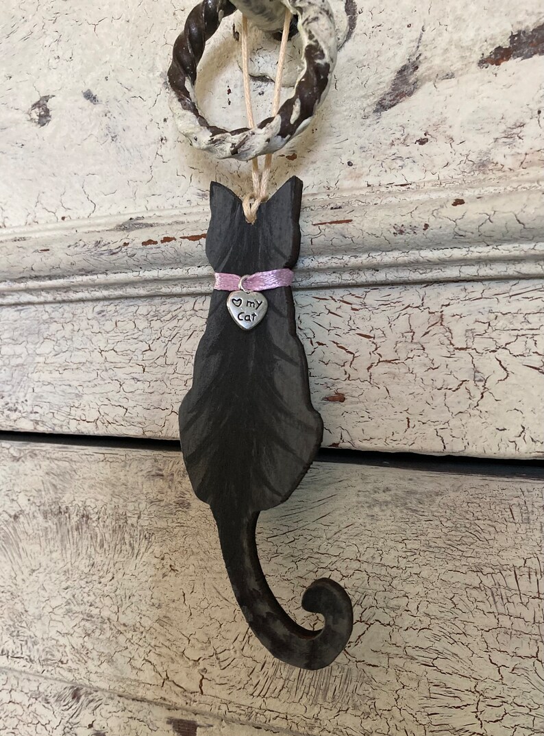 May include: Black wooden cat silhouette ornament with a pink ribbon and a silver charm that says "Love My Cat".
