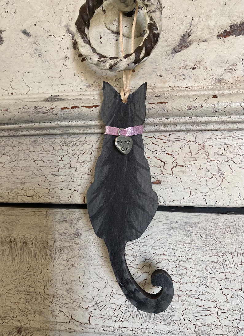 May include: Black wooden cat silhouette ornament with a pink ribbon and a silver charm that says "I love my cat".
