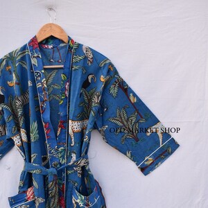 May include: A blue cotton robe with a white trim and a jungle print featuring zebras, leopards, toucans, and palm trees. The robe has a tie belt and two pockets.