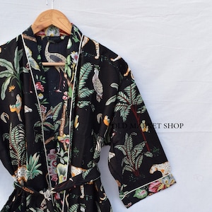 May include: Black silk robe with a white trim and a colorful jungle print featuring birds, zebras, and leopards. The robe has a tie belt and two pockets.