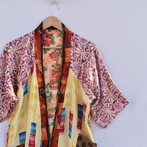 May include: A yellow, red, blue, and brown patchwork silk kimono with a floral print lining. The kimono has a V-neck and short sleeves.