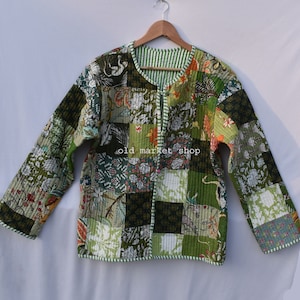 May include: A green quilted jacket with a patchwork design featuring floral and bird motifs. The jacket has a zipper closure and a striped lining.