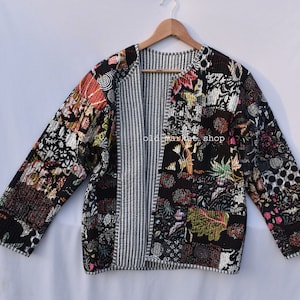 Może przedstawiać: Czarna pikowana kurtka z kwiatowym nadrukiem i podszewką w paski. Kurtka ma luźny krój i lekko skróconą długość. Na kurtce widoczny jest napis "old market shop".