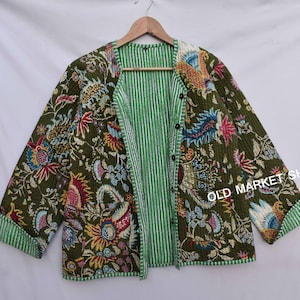 Op de afbeelding: Een groen gewatteerd jack met een bloemenprint en een gestreepte voering. Het jack heeft een knoopsluiting en is omkeerbaar.