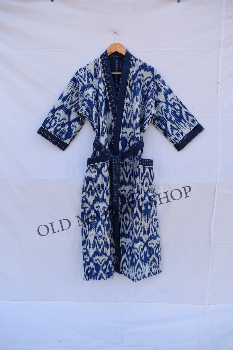 May include: A blue and white patterned robe with a tie belt. The robe is made of cotton and has a quilted design.