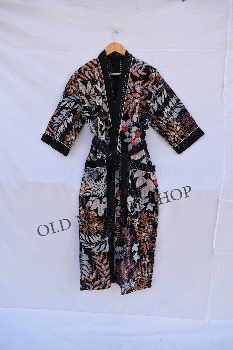 May include: A black floral print robe with a long sleeve and a tie belt. The robe has a quilted design and a white trim.