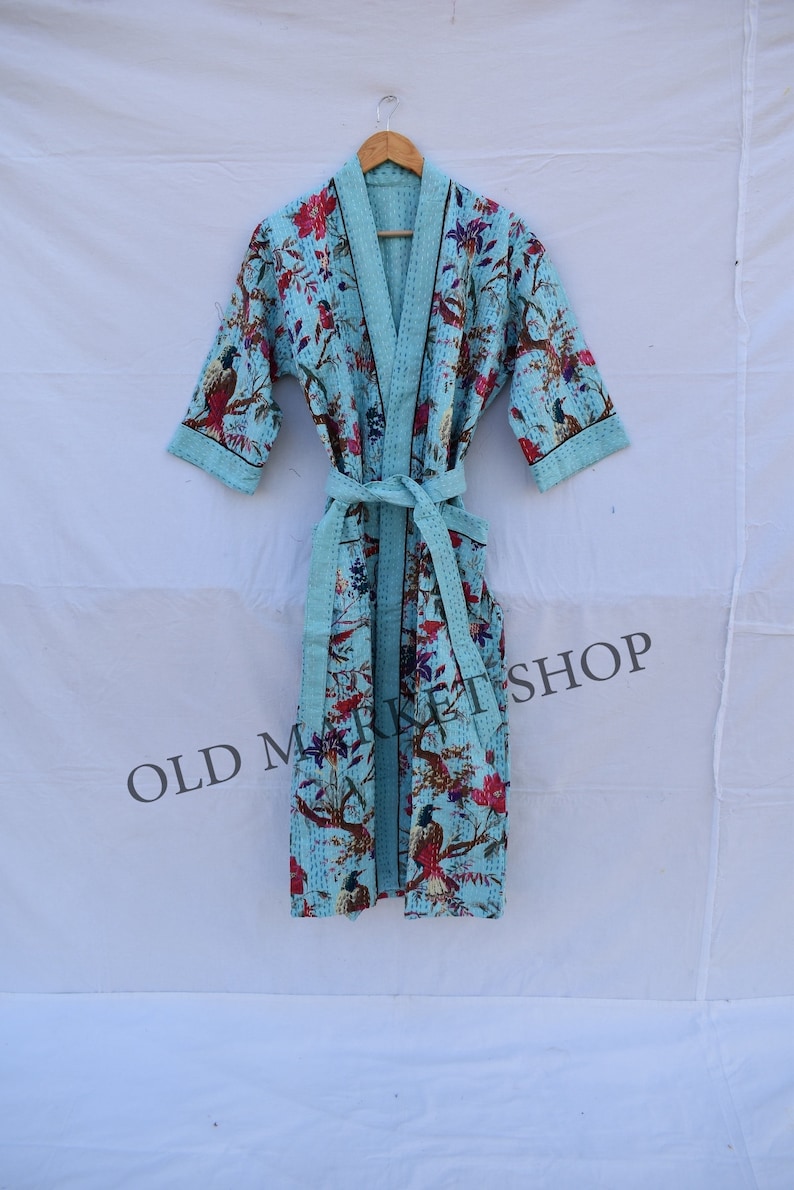 May include: A light blue robe with a floral print featuring birds and flowers. The robe has a black trim and a matching tie belt.