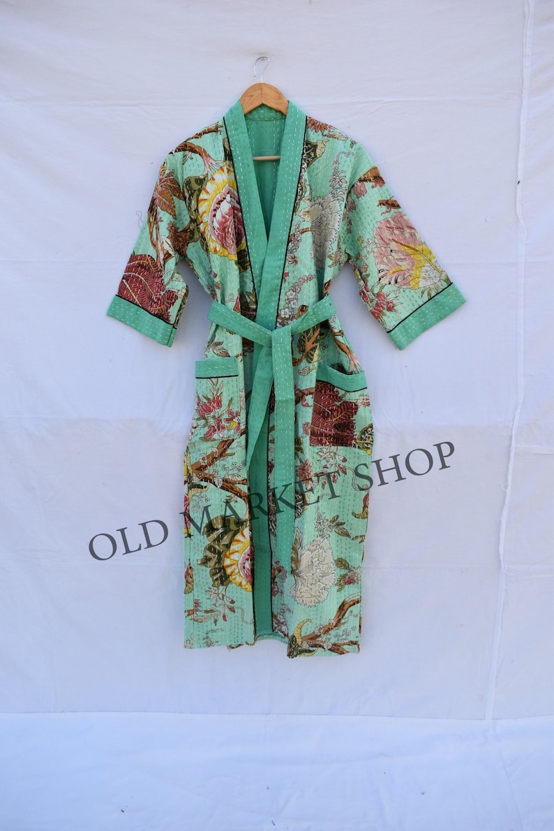 May include: A mint green floral patterned robe with a black trim and a matching sash. The robe has two pockets and is made of a soft, comfortable fabric. OLD MARKET SHOP is printed on the bottom of the robe.