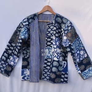 May include: A blue and white quilted jacket with a patchwork design. The jacket has a long sleeve and a button closure. The fabric is made of cotton and is soft and comfortable.