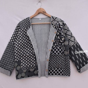 May include: Black and white quilted jacket with a striped lining and a button closure. The jacket is made of cotton and has a patchwork design.